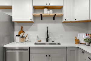 Kitchen featuring appliances with stainless steel finishes, light stone countertops, open shelves, and gray cabinets