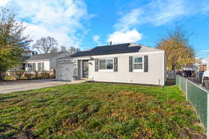 View of front of house with concrete driveway, roof mounted solar panels, and a garage