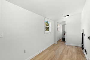 Hallway with vaulted ceiling and light wood-style flooring