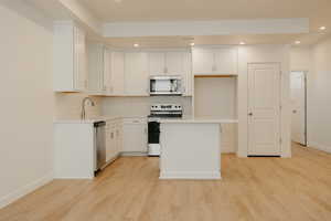 Kitchen with appliances with stainless steel finishes, white cabinetry, recessed lighting, a kitchen island, and light wood-style floors