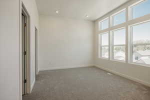 Empty room with light colored carpet and recessed lighting