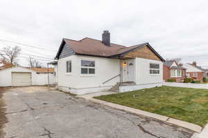 View of front of property featuring a chimney, an outdoor structure, a garage, and driveway