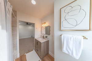 Full bath featuring vanity, a shower with curtain, ceiling fan, and light wood-style flooring