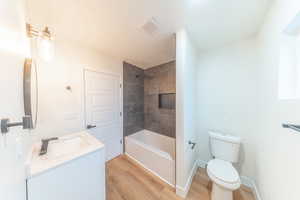 Bathroom featuring vanity, a textured ceiling, light wood finished floors, and shower / washtub combination