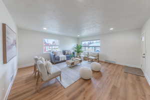 Living room with a textured ceiling, light wood-style floors, and recessed lighting