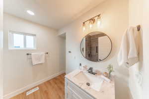 Full bath featuring vanity, light wood finished floors, a textured ceiling, and a tile shower