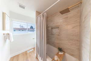 Full bath featuring shower / tub combo, light wood-type flooring, and a textured ceiling