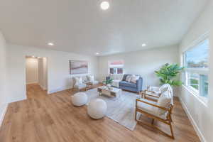 Living area with recessed lighting, light wood-style floors, plenty of natural light, and a textured ceiling