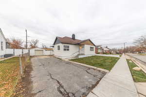 View of front of house with a detached garage, a chimney, an outbuilding, and asphalt driveway
