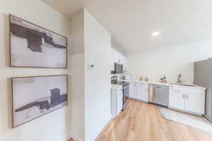Kitchen featuring appliances with stainless steel finishes, white cabinets, and light wood-style flooring