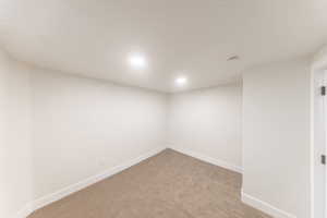 Unfurnished room featuring light carpet and baseboards