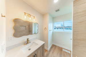 Bathroom with vanity, light wood-style floors, and a textured ceiling