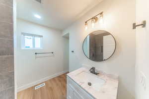 Bathroom featuring vanity, light wood-type flooring, a textured ceiling, and a tile shower