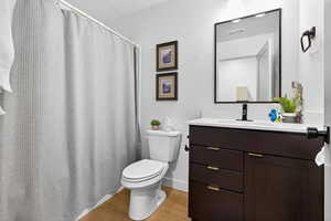 Bathroom featuring a shower with curtain, light wood finished floors, and vanity
