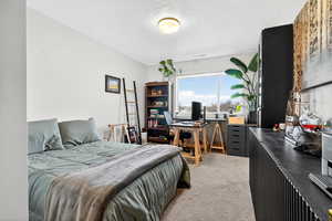 Bedroom featuring a desk, light colored carpet, and a textured ceiling