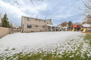 Snow covered house featuring a patio area, a playground, and a chimney