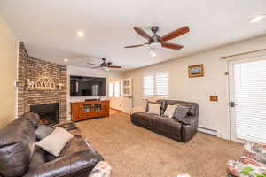 Living area with a brick fireplace, light carpet, a baseboard radiator, ceiling fan, and recessed lighting