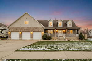View of front facade featuring covered porch, brick siding, concrete driveway, a garage, and a yard