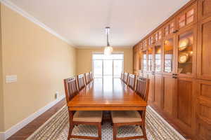Dining space featuring ornamental molding, light wood-style floors, and a textured ceiling