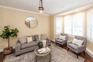 Living area with ornamental molding and wood finished floors