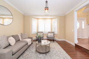Living room with ornamental molding and wood finished floors