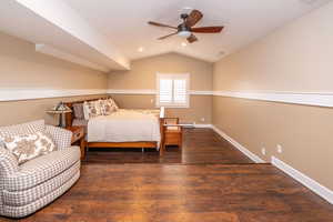 Bedroom featuring dark wood finished floors, lofted ceiling, and a ceiling fan