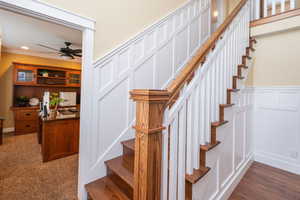 Stairs with a decorative wall, ceiling fan, recessed lighting, and wainscoting