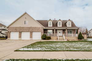 View of front facade with brick siding, a porch, driveway, a garage, and a front yard