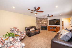 Living area featuring a brick fireplace, light colored carpet, a ceiling fan, and recessed lighting