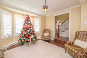 Sitting room with wood finished floors, stairway, and crown molding