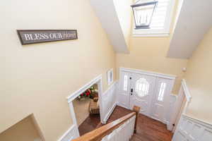 Entrance foyer featuring plenty of natural light, dark wood finished floors, stairs, a towering ceiling, and a skylight