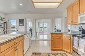Kitchen with a peninsula, plenty of natural light, white appliances, recessed lighting, and light brown cabinetry