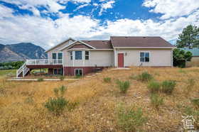 Rear view of house featuring a deck with mountain view, stairway, and stucco siding