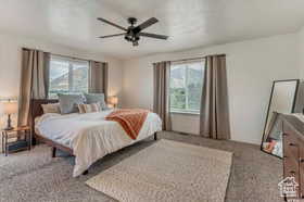 Bedroom with light carpet, multiple windows, and a ceiling fan