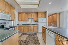 Kitchen with dark countertops, white appliances, and recessed lighting