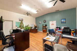 Office area with ceiling fan, lofted ceiling, light wood-style floors, and a textured ceiling