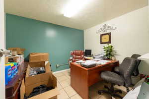 Office space with a textured ceiling and light tile patterned floors