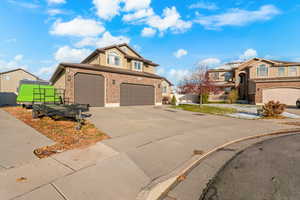Traditional-style home featuring stucco siding, driveway, a garage, brick siding, and a residential view
