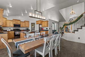 Dining area with stairs, vaulted ceiling, dark tile patterned flooring, and a chandelier