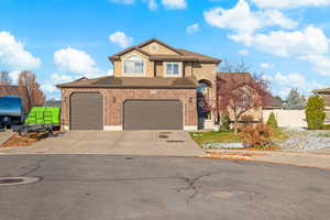 View of front of property featuring concrete driveway, brick siding, stucco siding, and an attached garage