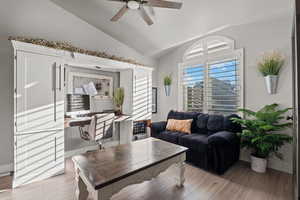 Living room with an office area, vaulted ceiling, wood finished floors, and a ceiling fan