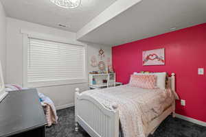 Bedroom with dark carpet and a textured ceiling