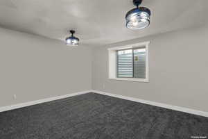Unfurnished room with baseboards and dark colored carpet