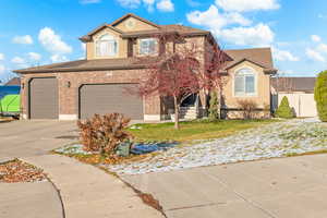 Traditional-style house with driveway, brick siding, stucco siding, roof with shingles, and a garage