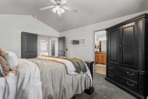 Bedroom featuring ensuite bath, lofted ceiling, a ceiling fan, and light carpet