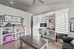 Office space with vaulted ceiling, a ceiling fan, and wood finished floors