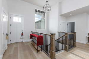 Foyer featuring healthy amount of natural light, light wood finished floors, and a chandelier