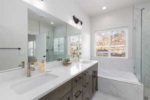 Bathroom with double vanity, a garden tub, and a marble finish shower