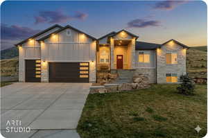 Contemporary home with stone siding, board and batten siding, an attached garage, and concrete driveway