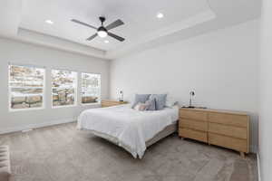 Carpeted bedroom with a raised ceiling, ceiling fan, and recessed lighting